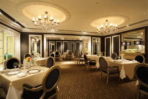 大阪大阪日航国际酒店的餐厅设有白色的桌椅和吊灯。