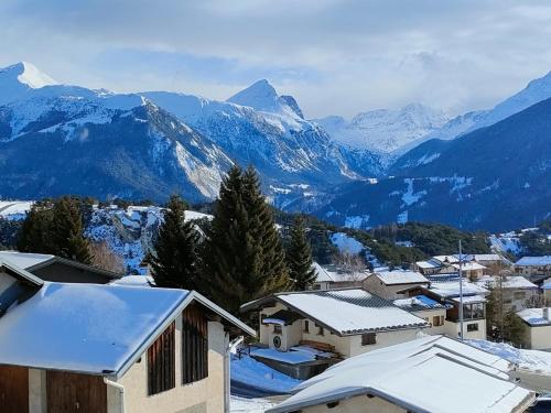 欧苏瓦Fleur et Benj的一座有雪盖屋顶和山脉的城镇