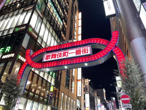 东京HOTEL AMANEK Shinjuku Kabukicho的建筑中间的一个红色大标志