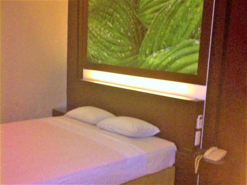 班贾尔马辛Citra Raya Hotel Banjarmasin的一张带两个枕头的床铺,放在画底下