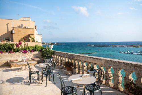 奥特朗托帕拉佐德摩利酒店的一个带桌椅的庭院,俯瞰着大海