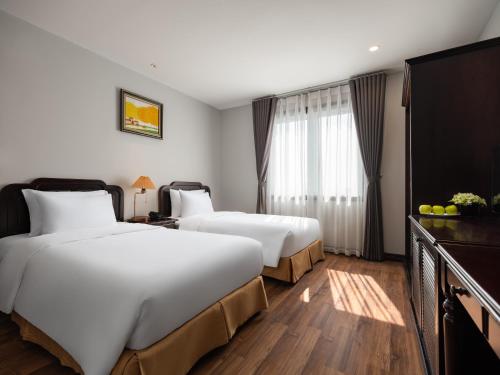 河内Minasi Premium Hotel的酒店客房设有两张床和一台平面电视。