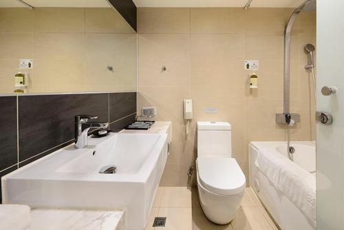 台中市碧根逢甲酒店的浴室配有盥洗盆、卫生间和浴缸。