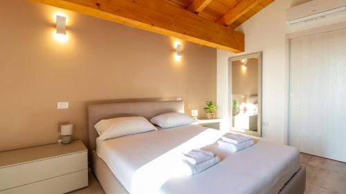 奥里斯塔诺Casa Degli Artigiani-Attico con vista的卧室配有一张白色大床和镜子