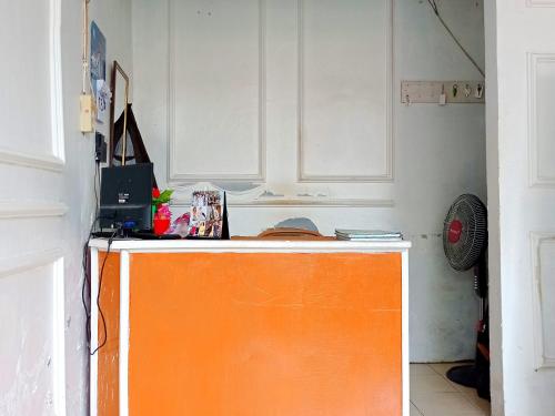 明古鲁省Reddoorz @ Kanaka GuestHouse的厨房里有一个橙色的柜台,有白色的橱柜
