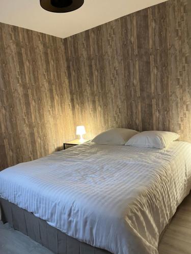 福龙河畔拉罗什Le troubadour的一间卧室设有一张带木墙的大床
