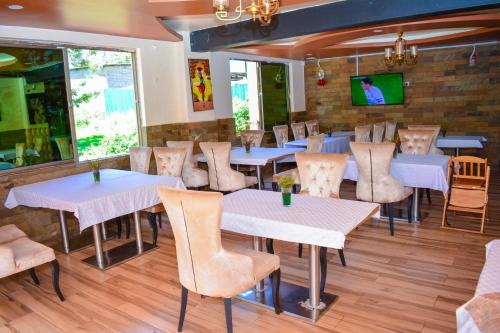 KaratinaOmega Gardens Hotel的一间带桌椅的餐厅以及砖墙