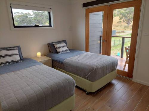Surveyors BayThe Beach Box at Big Roaring Beach Tasmania的一间卧室设有两张床,并设有一个通往庭院的门。
