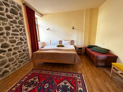 戈里斯Saryan Guesthouse的一间卧室配有一张床、一张沙发和石墙