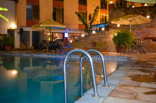 KaratinaOmega Gardens Hotel的一座带椅子和遮阳伞的游泳池位于一座建筑旁边