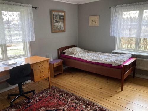 林德斯贝里Setons Stuga的卧室配有一张床、一张书桌和窗户。
