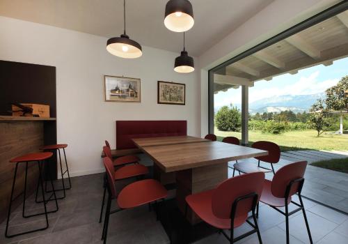 特伦托Agritur Ponte Alto的一间带木桌和红色椅子的用餐室