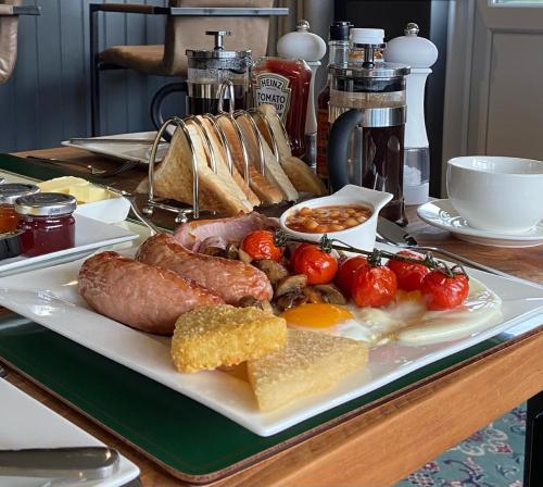 WeobleyMarshpools Bed & Breakfast - Licensed near Weobley village的餐桌上放着一盘带香肠和西红柿的食物