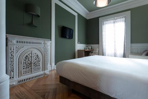 马德里利尔塔德广场小皇宫酒店的卧室配有白色的床和壁炉