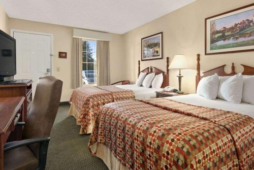 尤福拉Baymont by Wyndham Eufaula的酒店客房设有两张床、一张桌子和一台电视。