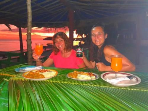 玛娜岛Mana Lagoon Backpackers的坐在餐桌上吃盘子的男人和女人