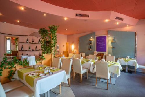孔茨Park Hotel的一间设有白色桌椅的餐厅,种植了植物