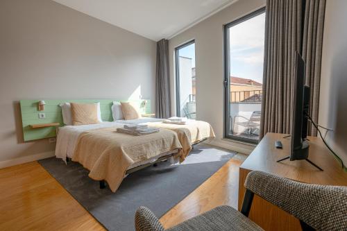 波尔图Oporto Trendy Formosa的一间卧室设有一张床、一台电视和一个阳台。