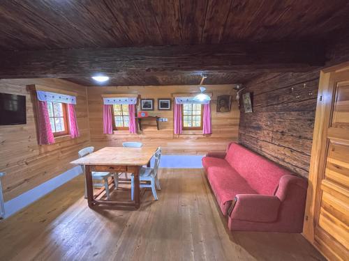 PrevaljeEco tourist farm Mikl的客厅配有桌子和红色沙发