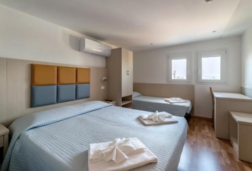 里米尼斯特雷萨酒店的一间卧室配有两张带毛巾的床