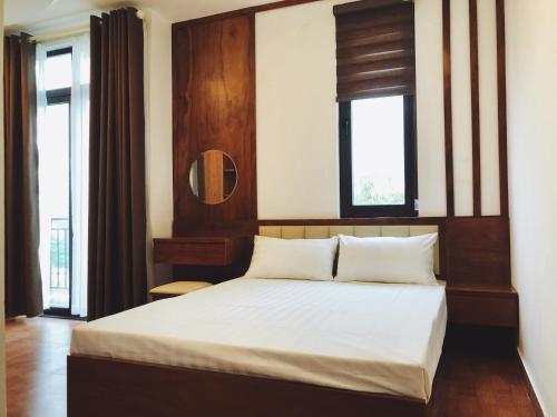 海防Đức Tuân 2 Motel的一间卧室配有一张带白色床单的床和两个窗户。