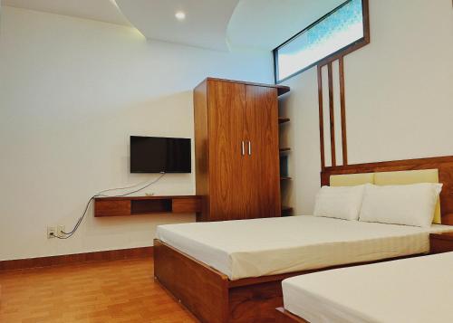 海防Đức Tuân 2 Motel的卧室配有一张床,墙上配有电视。