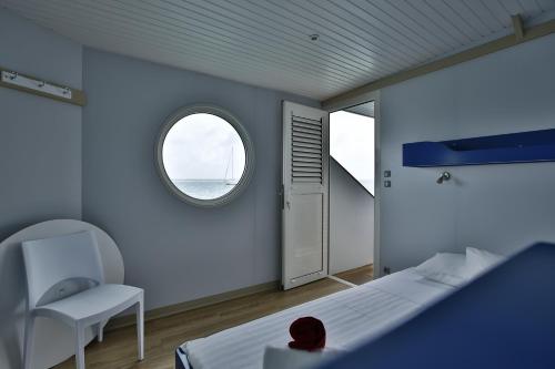 豪特尔Aqualodge, Les Saintes, Terre de Haut的一间卧室设有一张床、一个窗口和一把椅子