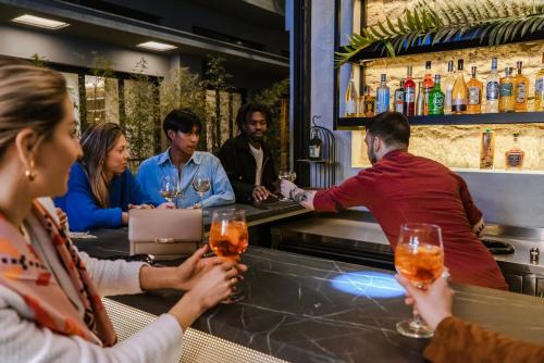 雅典Mosaikon Glostel的一群人坐在酒吧里,戴着酒杯