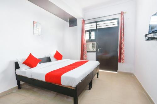 加济阿巴德OYO Hindon Residency的一间卧室配有一张带红色枕头的床和一扇窗户
