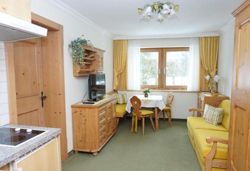 佩尔蒂绍Landhaus Achental的厨房以及带桌子和黄色沙发的客厅。