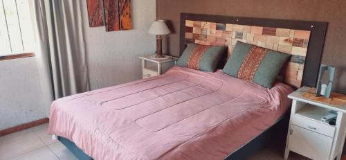 卢汉德库约El descanso, zona de bodegas的一间卧室配有一张带粉色毯子的大床