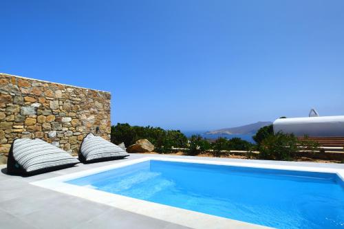 帕诺尔莫斯米科诺斯Sea Breeze Mykonos的一座带枕头的游泳池,毗邻石墙