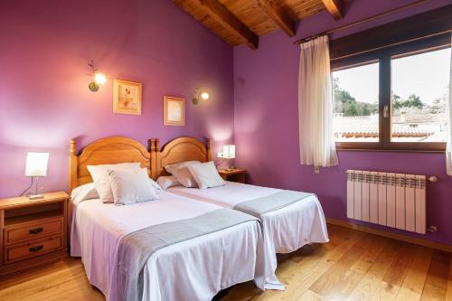 纳韦斯Llanes Asturias的卧室设有两张床铺和紫色墙壁