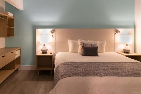 自由港市派力肯湾酒店的一间卧室配有一张大床,桌子上放着两盏灯