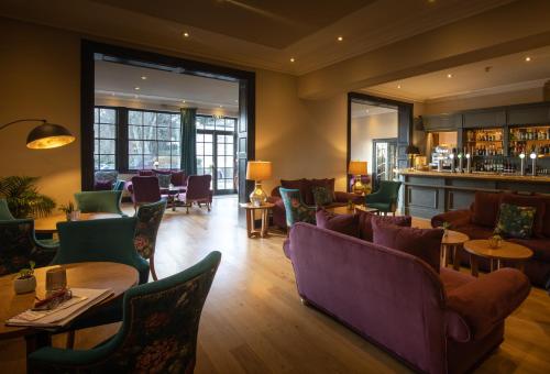 切斯特Rowton Hall Hotel and Spa的一间带沙发和桌子的餐厅和一间酒吧