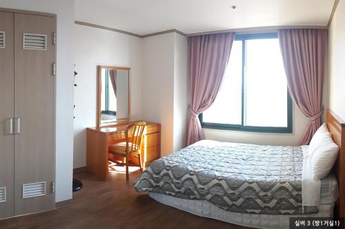 尤九南韩河伊尔松公寓的一间卧室配有一张床、一张书桌和一个窗户。