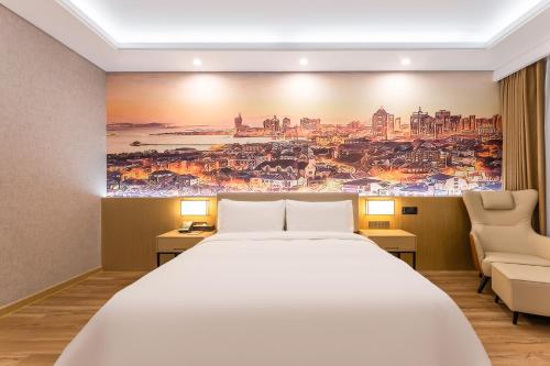 胶州青岛胶东国际机场秋临悦享酒店的卧室配有一张大床,墙上挂有绘画作品