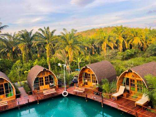 攀牙Plaiphu Pool Villas的一个带游泳池和棕榈树的度假村