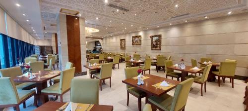 麦加Al Safwah Hotel First Tower的餐厅设有木桌和绿色椅子