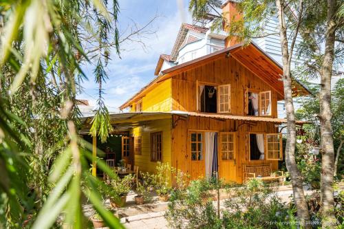 大叻Lam Vien Garden Villa - Homestay Da Lat的木房子,设有开放式窗户和树木
