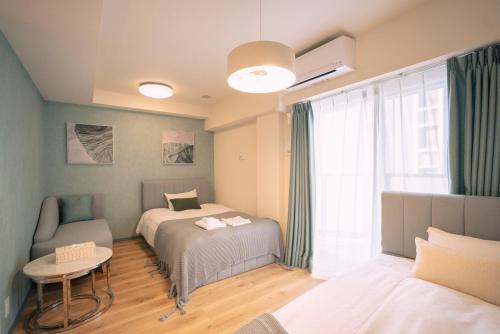 大阪谷町君HOTEL 心斎橋東32的一间卧室设有两张床、一张桌子和一个窗口