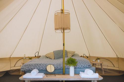 雷克桑德Sjugare Gård Glamping的一张位于帐篷内的床位,帐篷配有桌子上的两顶帽子