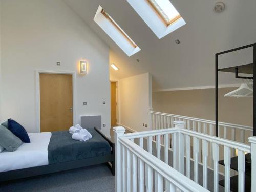 斯旺西Modern Duplex Apartment with Woodland Views的一间卧室设有一张床,楼梯设有天窗