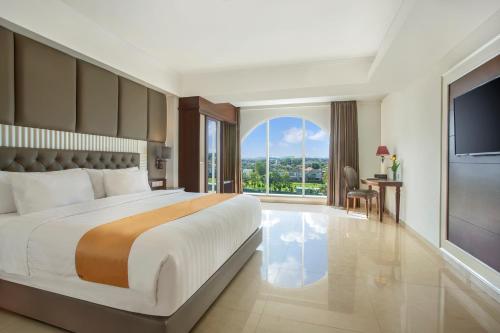日惹Grand Rohan Jogja的一间卧室设有一张大床和一个大窗户