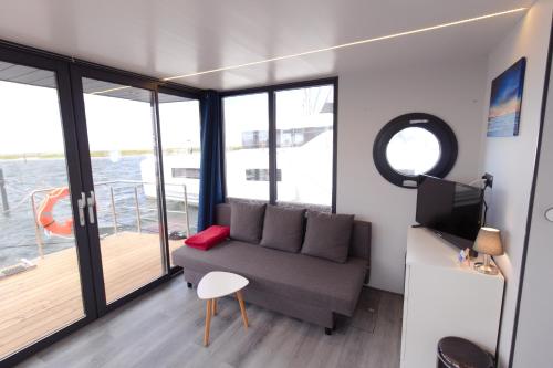 温德托尔夫Hausboot Fjord Aquila mit Dachterrasse in Wendtorf的带沙发的客厅和阳台