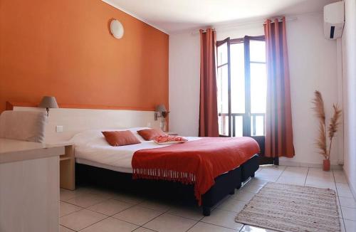 森图里Hôtel de la jetée的一间卧室配有一张带红色床单的床和一扇窗户。