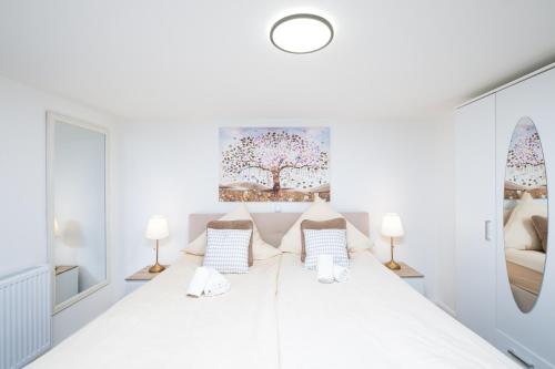 格斯塔特Gästehaus "Kleines Stadtidyll" -Zimmer und Apartments by Hotel Holsteiner Hof-的白色卧室配有一张带两盏灯的大床