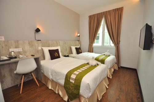 怡保艺术小屋酒店的酒店客房设有两张床、一张桌子和一台电视。