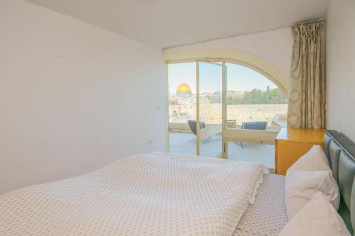 耶鲁沙拉伊姆Western Wall View Apartment的一间卧室设有一张床和一个美景窗户。