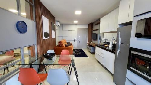 大坎普Estúdio Ultra Luxo com Vista Panorâmica的客厅配有玻璃桌和橙色椅子